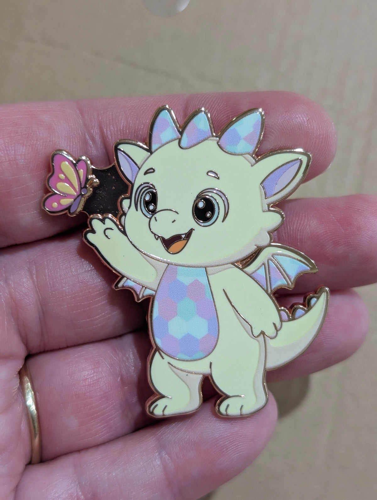 Opaliath dragon enamel pin held in hand