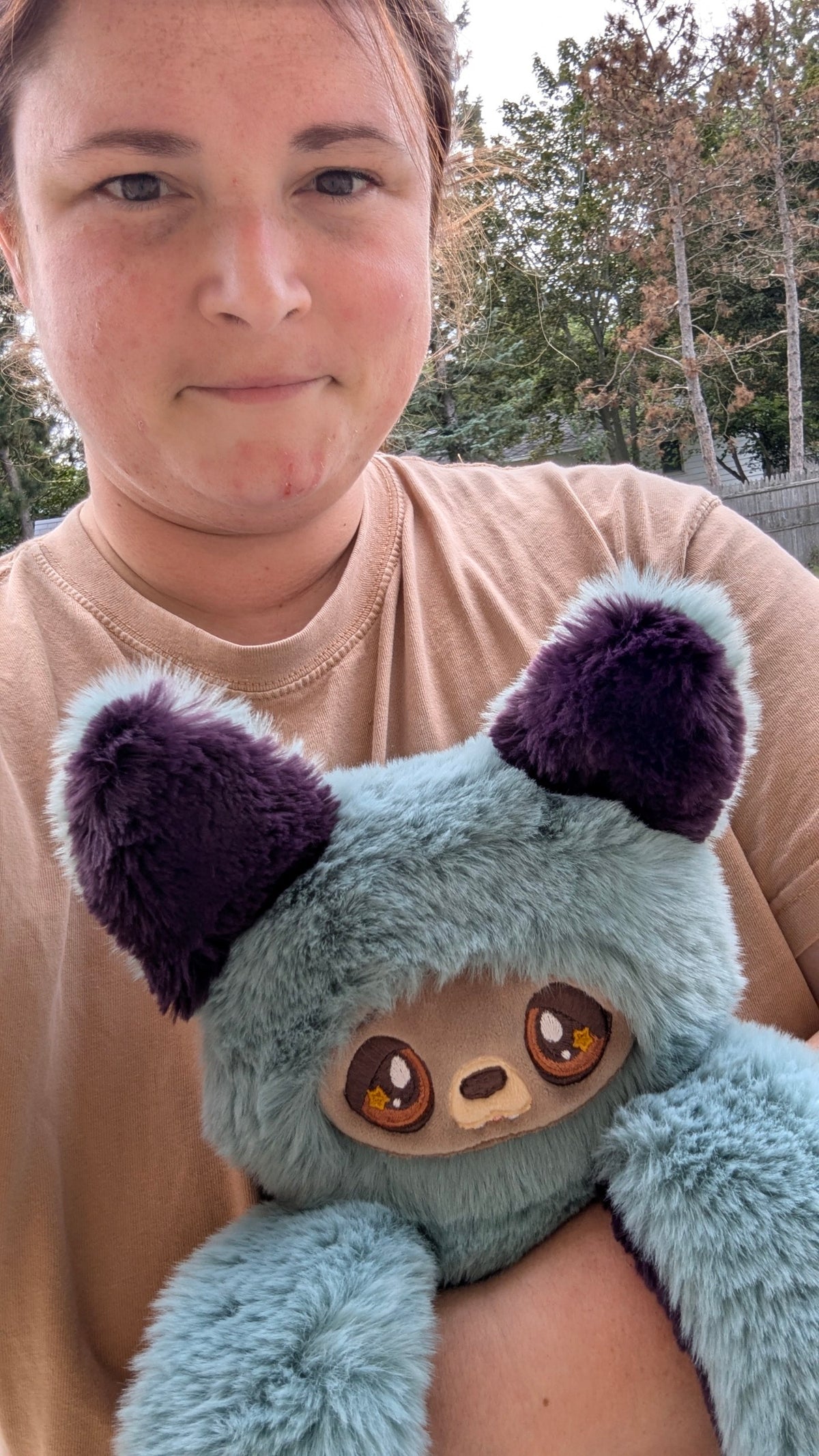 Evvies Lovies Jasper Noodle Wolf Pup plush with teal fur, purple ears, and amber eyes with star accents held by a person